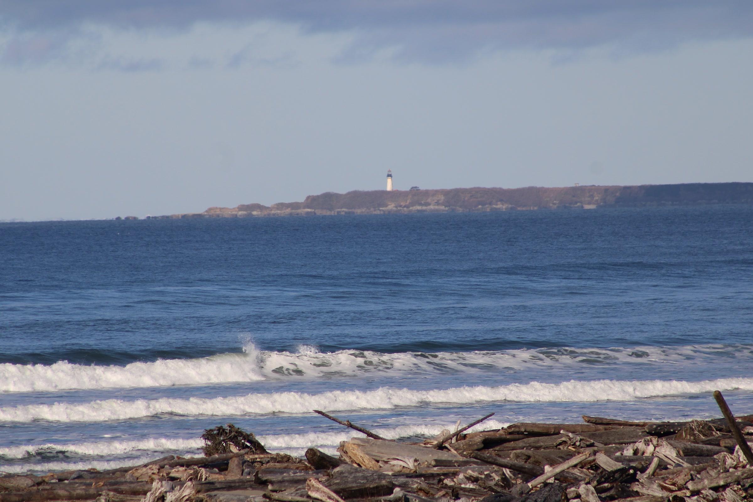 Destruction Island and its lighthouse on the horizon beyond breaking waves, seen from Kalaloch Campground in February 2025