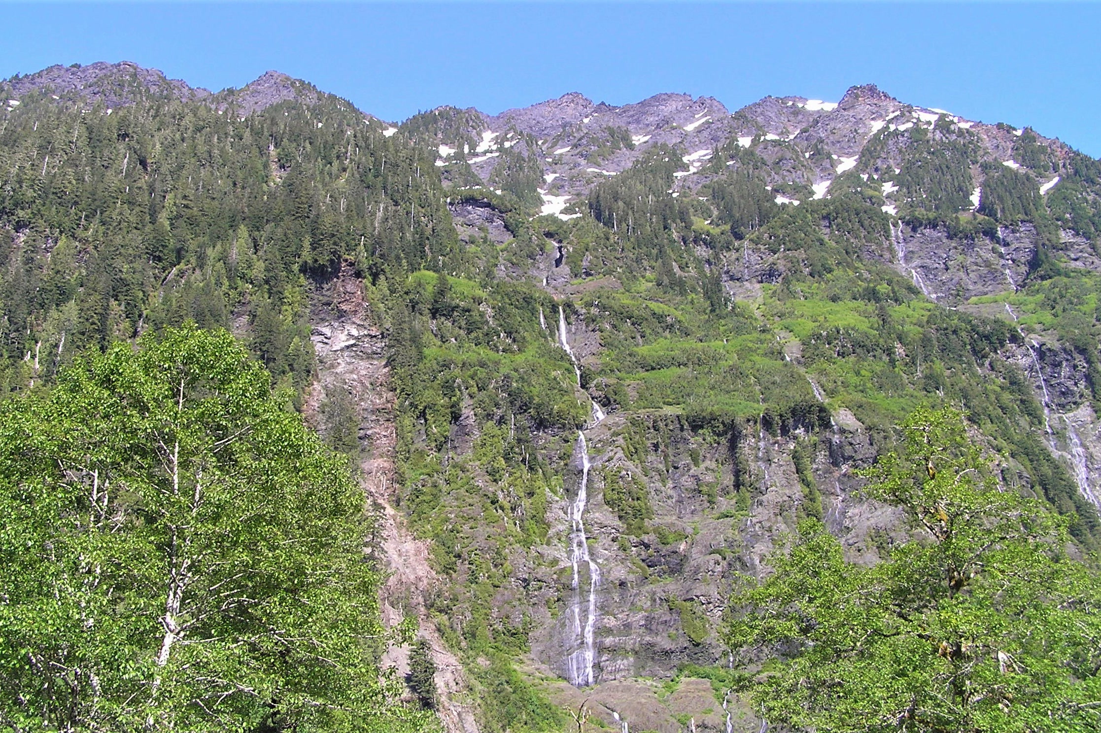 Thin waterfalls streaming down green cliffs on the slopes of Chimney Peak above Enchanted Valley