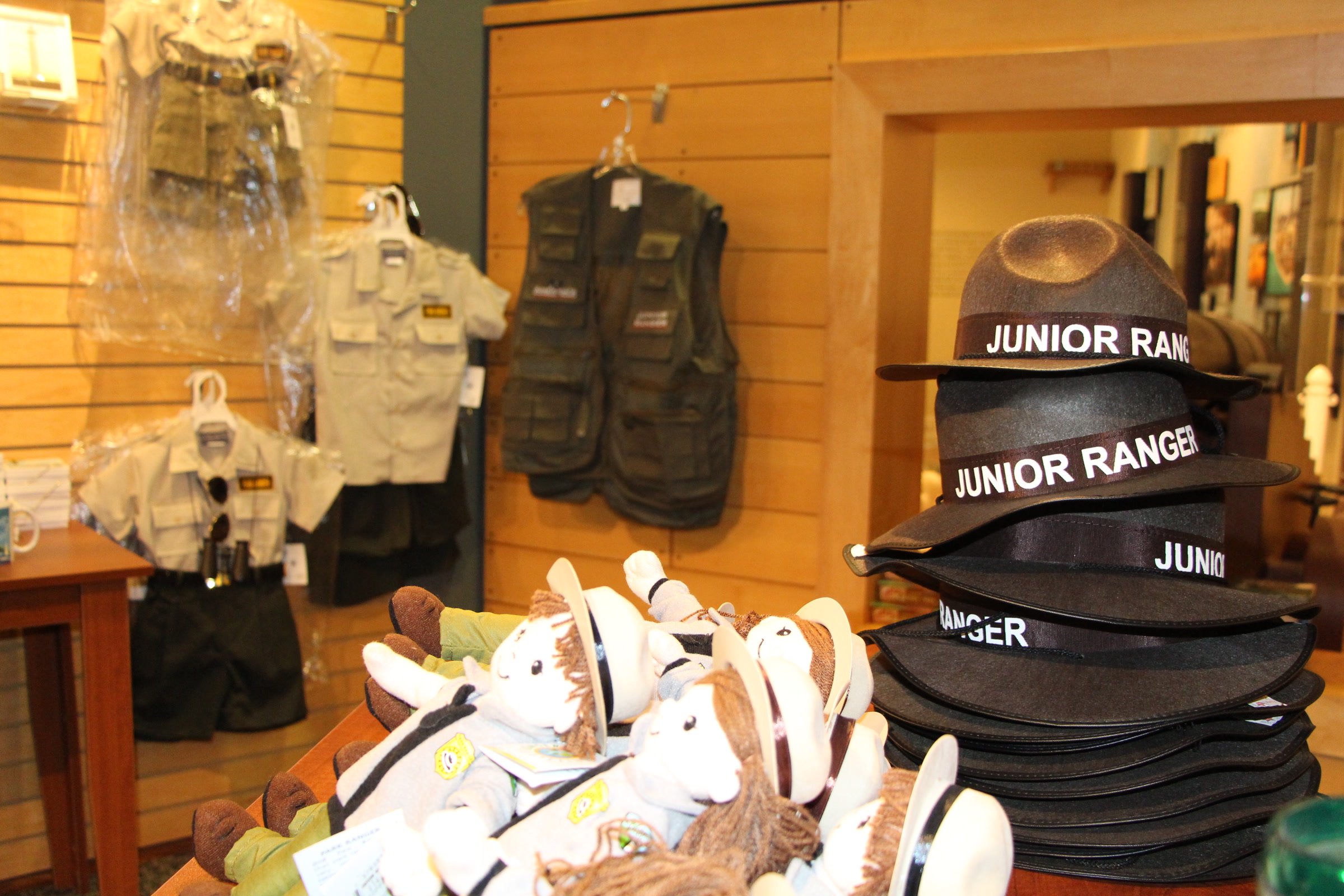 Stacked Junior Ranger hats, child-size ranger vests and plush toys on display in a park visitor center