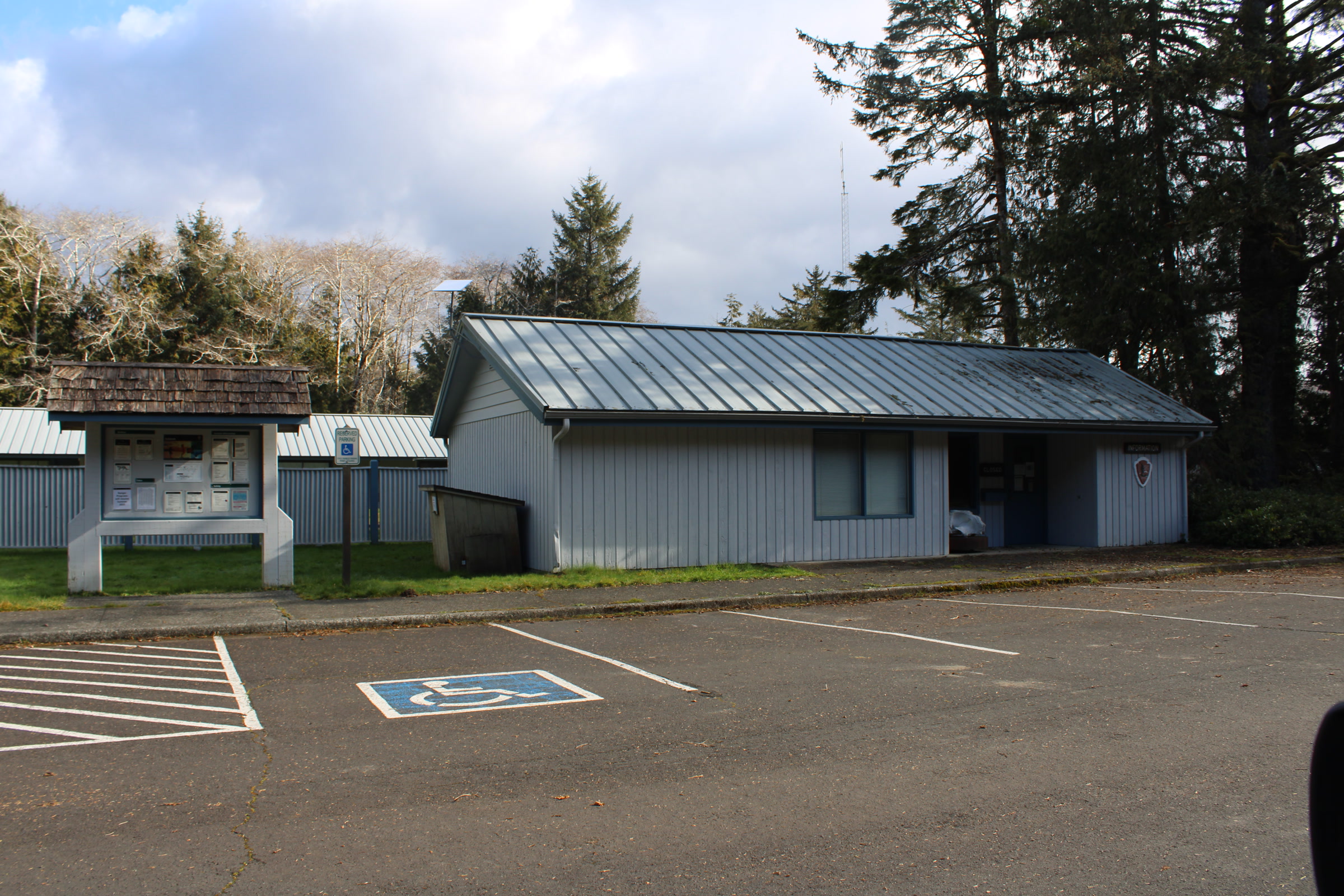 The grey Kalaloch Ranger Station building and an information board beside an empty parking lot
