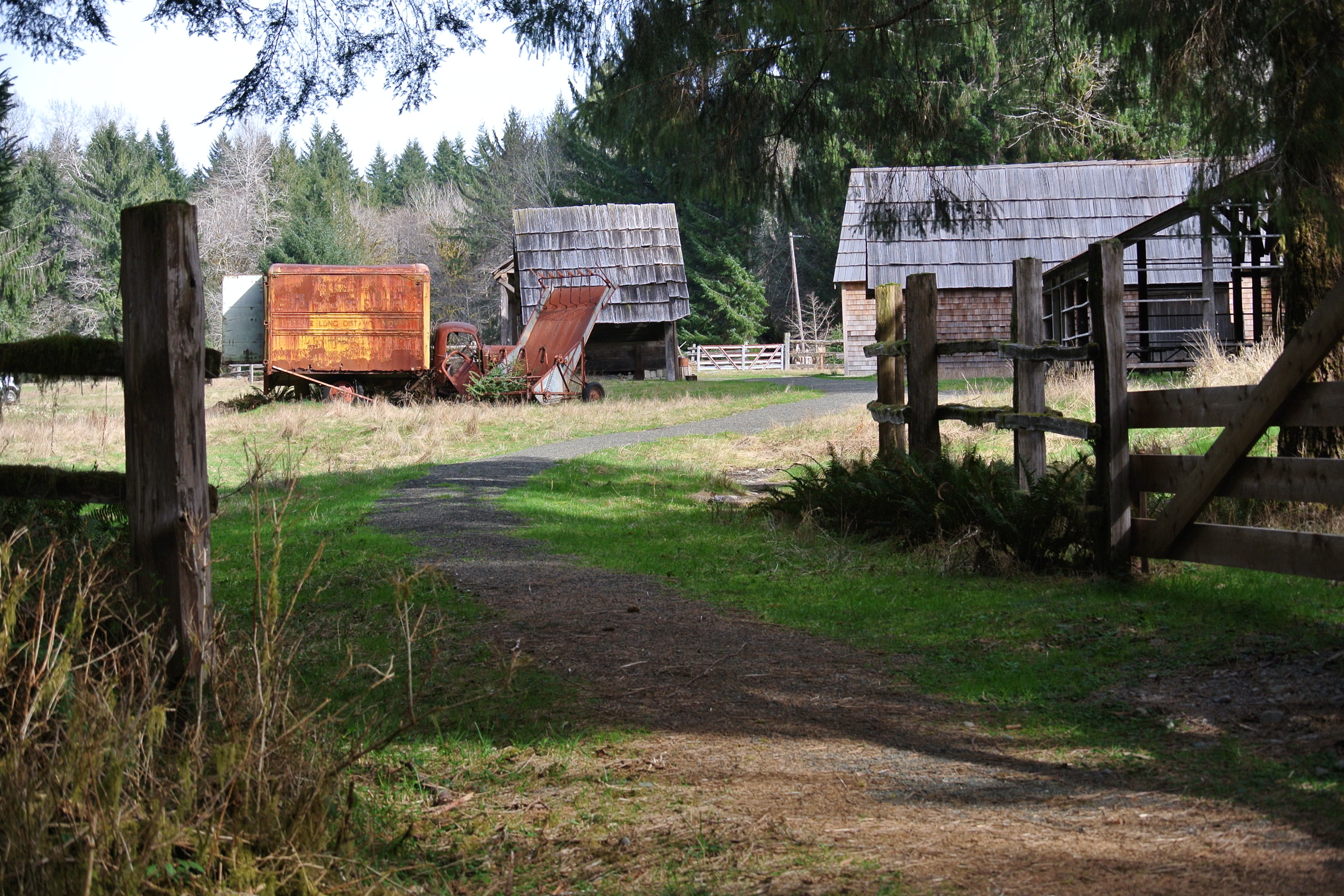 A gravel path beside a wooden fence leading to the old barns, sheds and a rusty truck at the Kestner Homestead