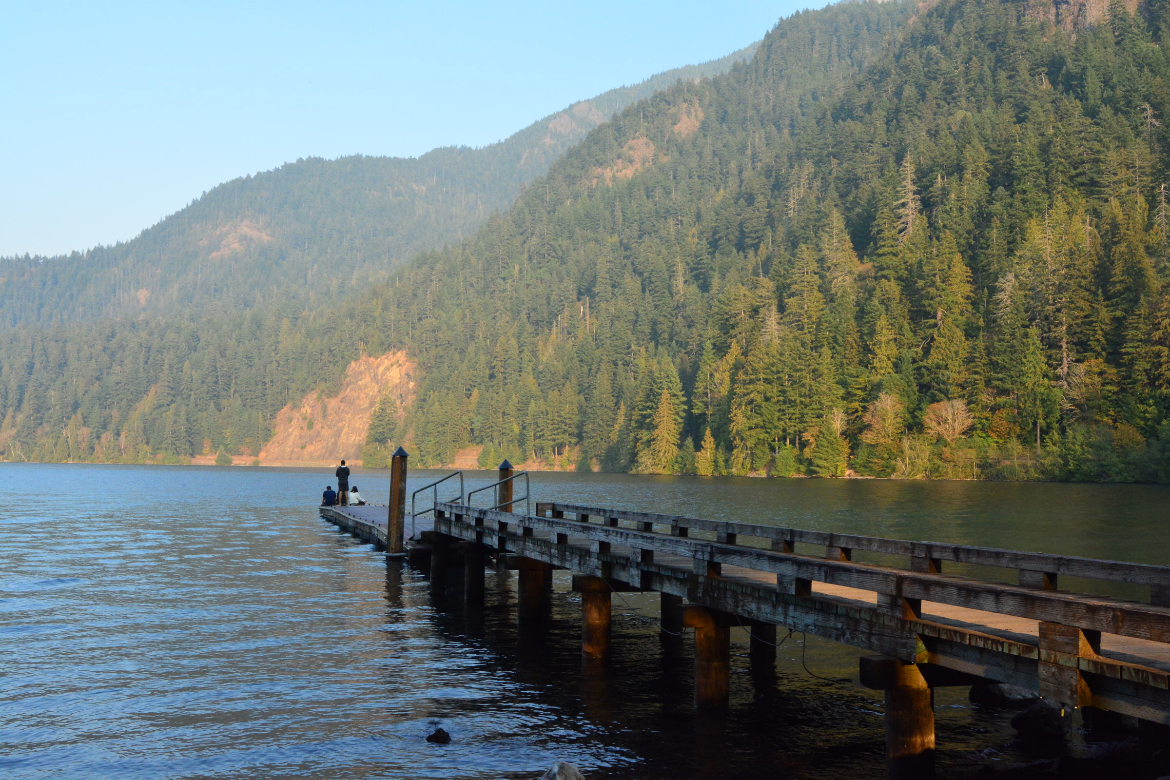 A long wooden pier reaching into calm Lake Crescent near Storm King Ranger Station, with forested mountains rising behind