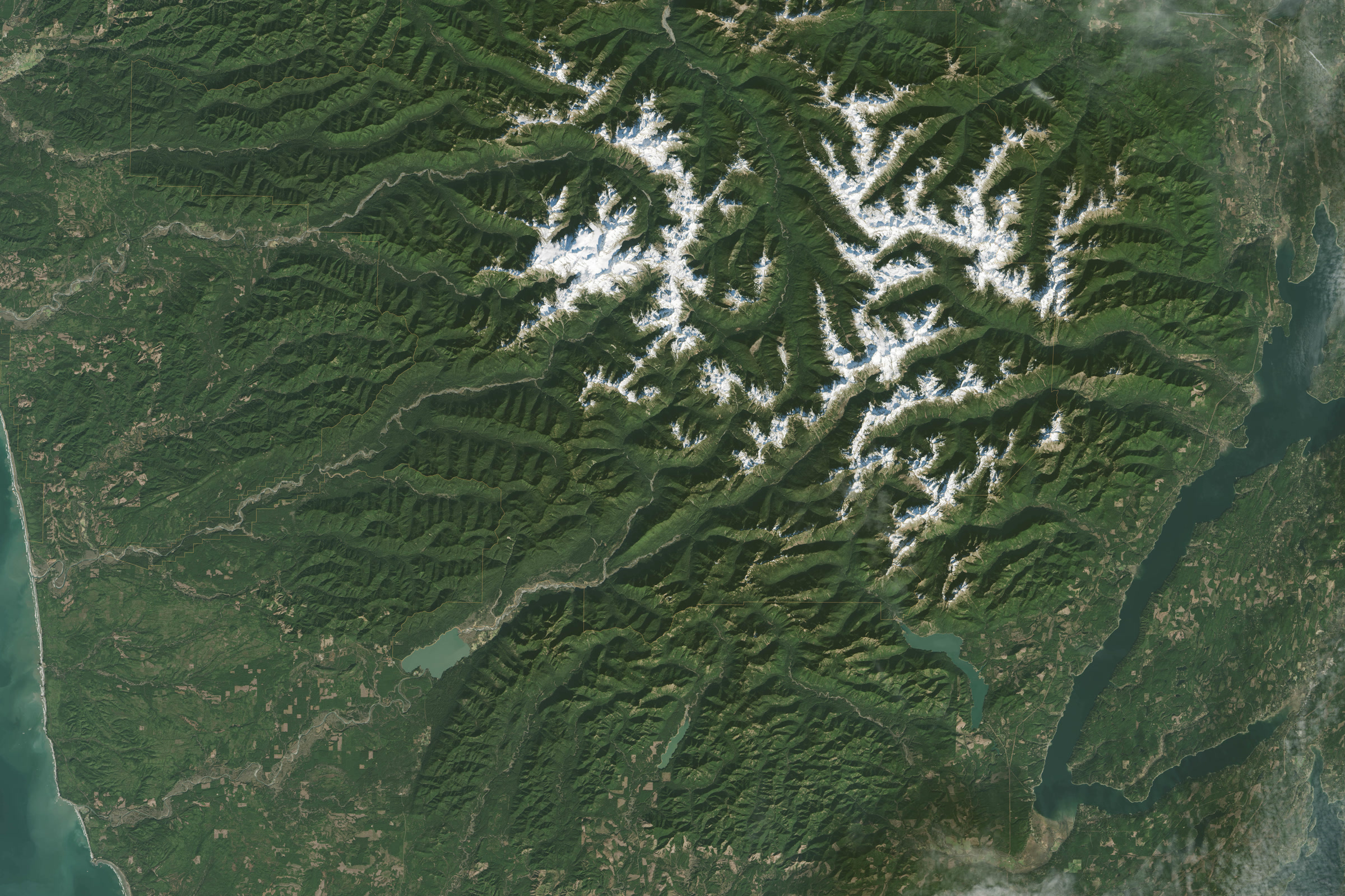 Satellite view of the Olympic Mountains, with snowy peaks in the centre surrounded by green forested ridges and river valleys