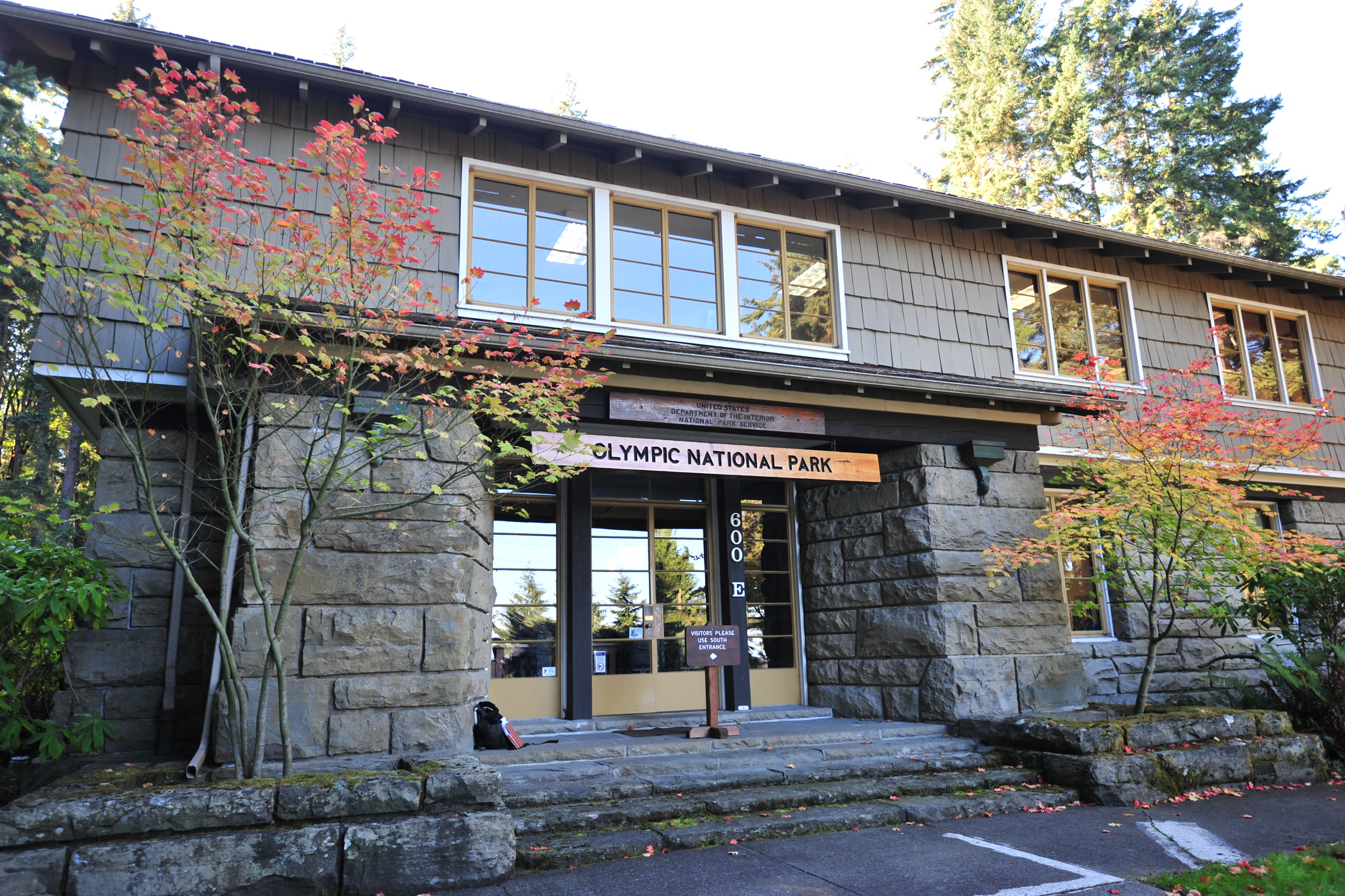 Stone-and-shingle entrance of Olympic National Park Headquarters near Port Angeles, framed by autumn foliage