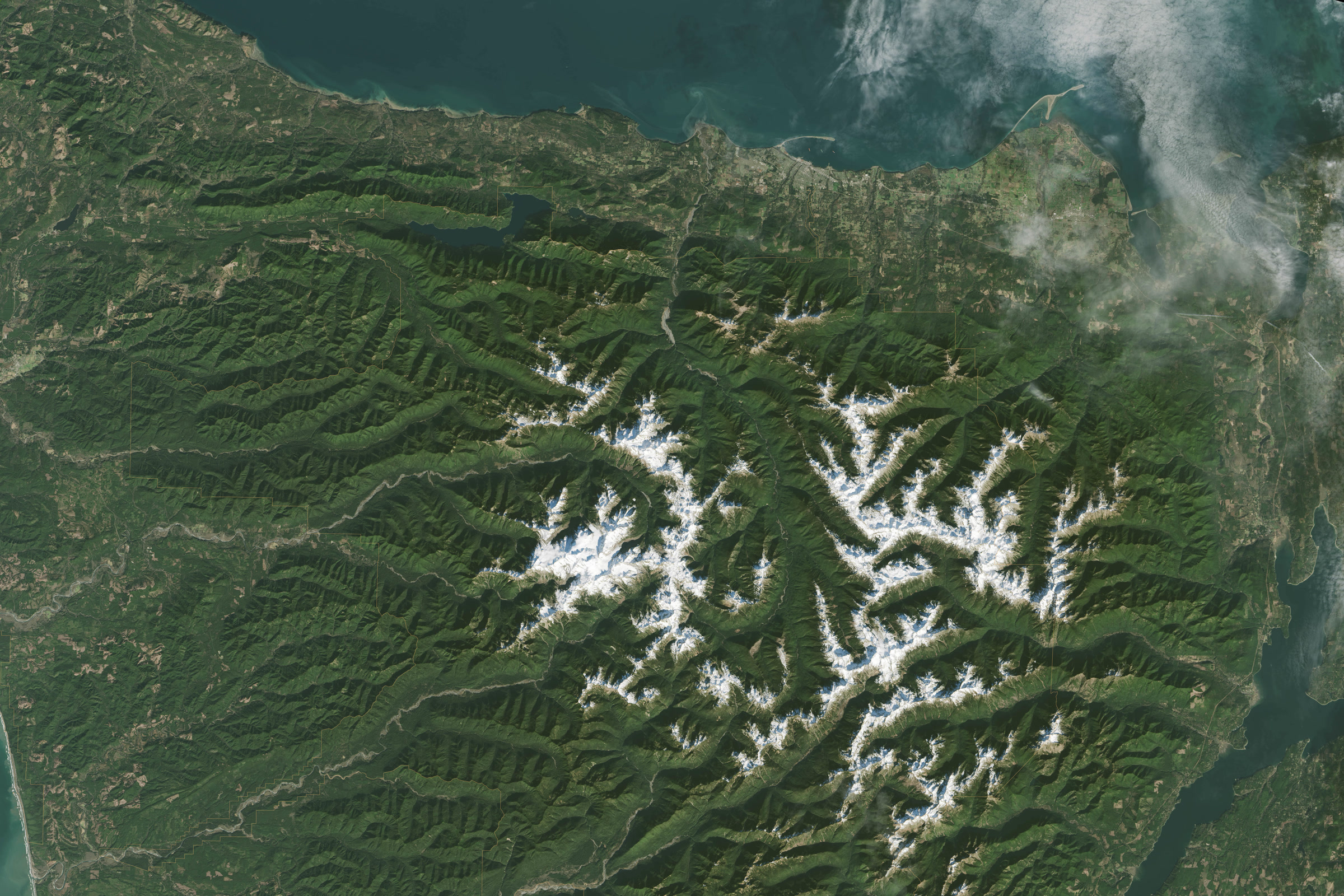 Satellite view of the Olympic Peninsula showing the snow-capped Olympic Mountains, green forested valleys and the Strait of Juan de Fuca along the north shore