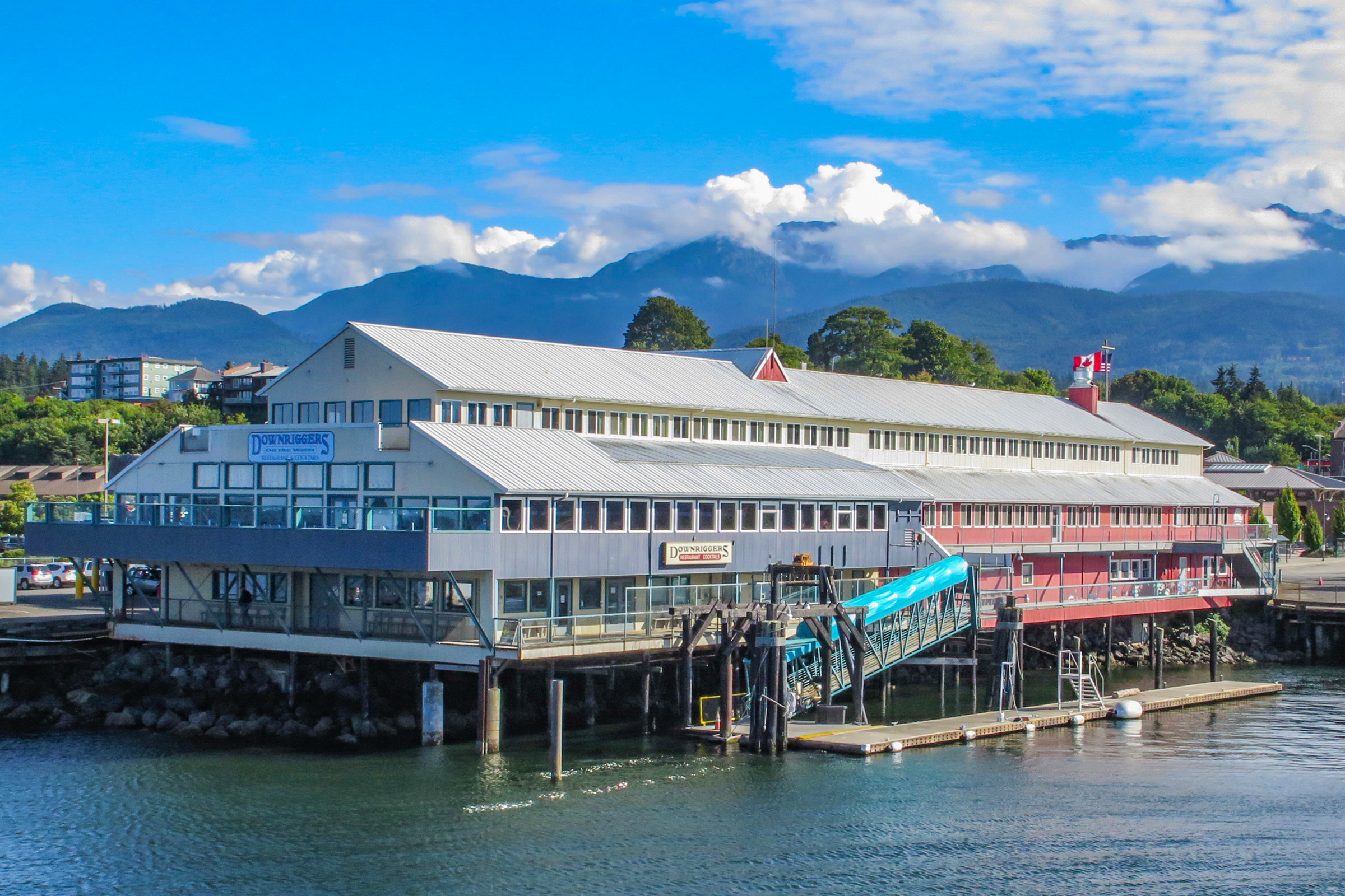 The ferry terminal building on the Port Angeles waterfront, with green foothills and cloud-topped Olympic peaks behind