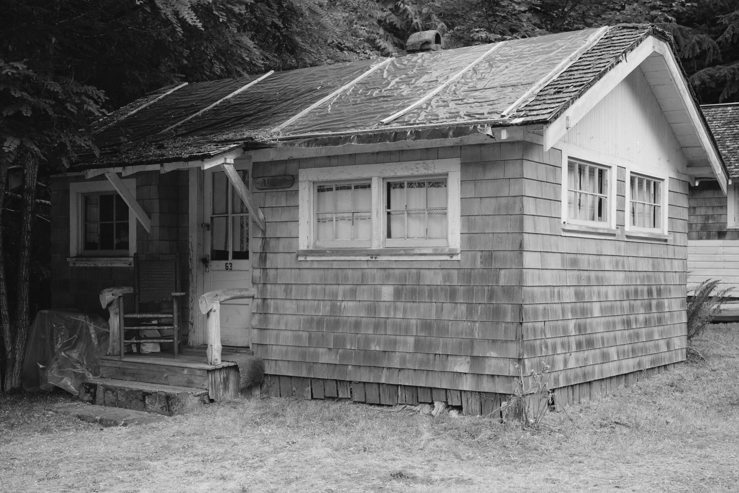 Black-and-white survey photo of a small shingled guest cabin at Rosemary Inn with a gabled porch and multi-pane windows