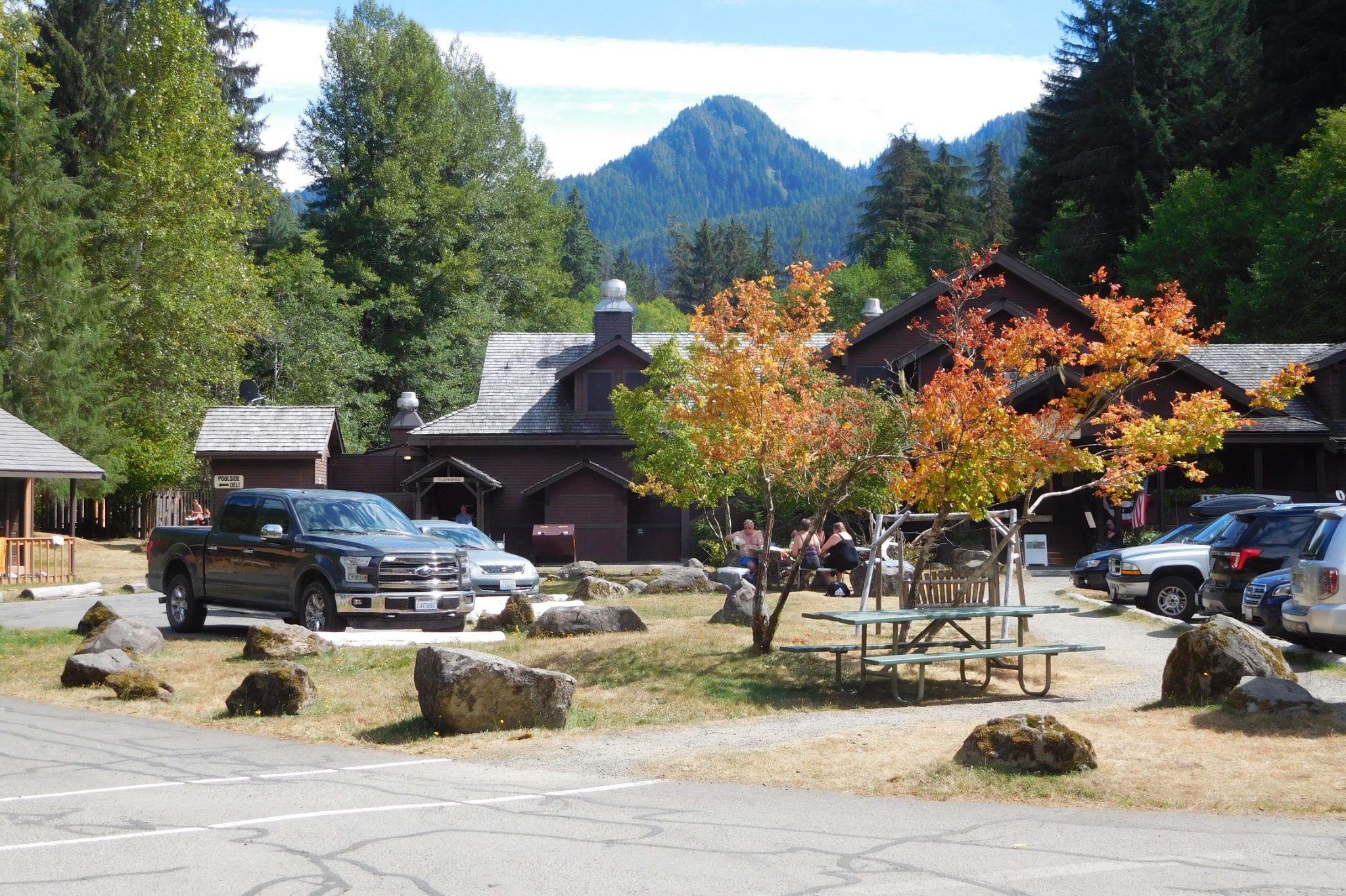 The lodge buildings and parking area of Sol Duc Hot Springs Resort framed by autumn leaves and a forested peak