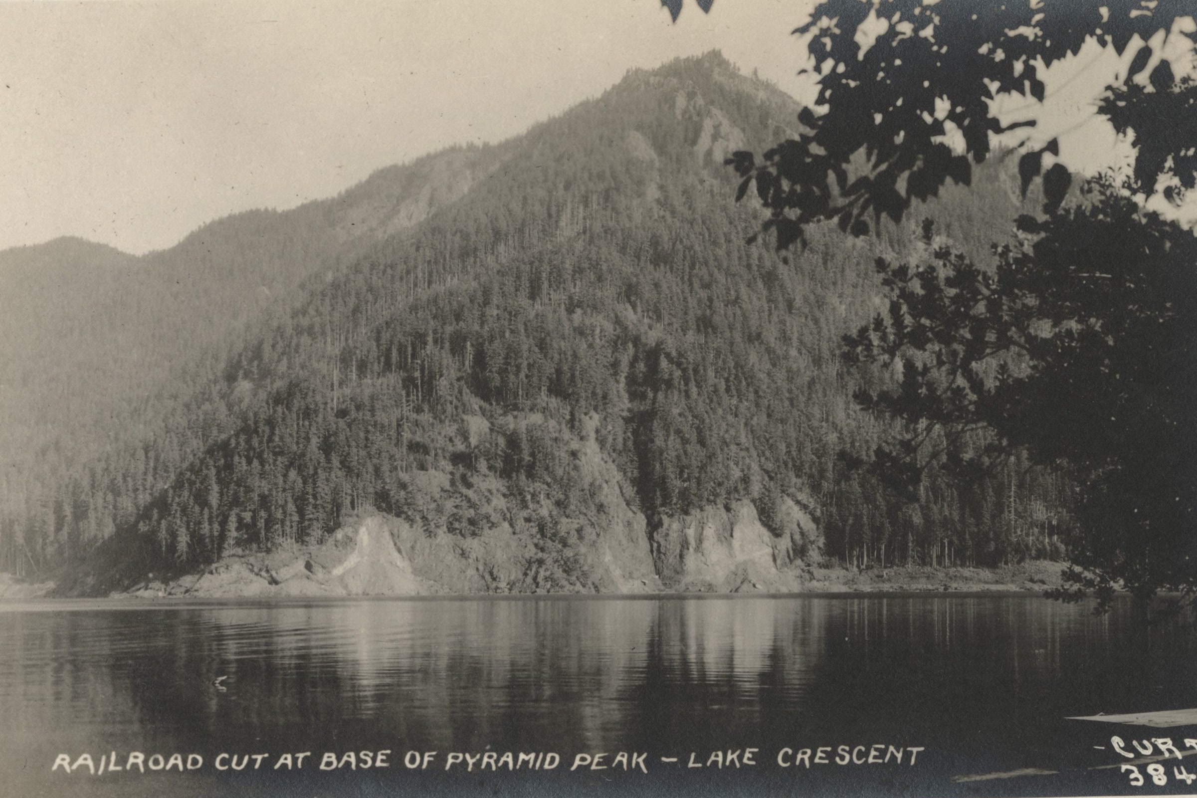 A black and white photograph from about 1925 of the railroad cut at the base of Pyramid Peak on the north shore of Lake Crescent